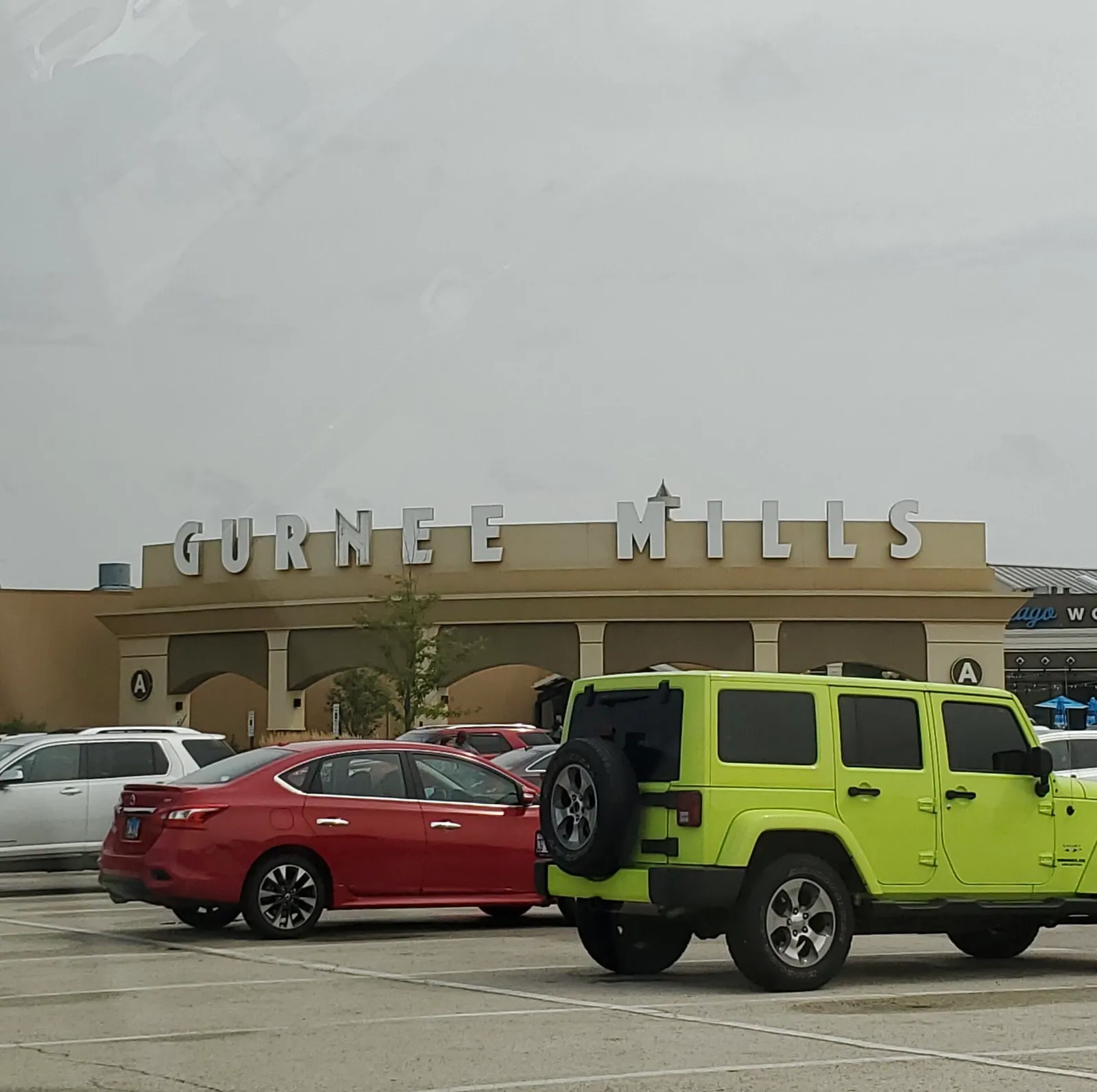 Gurnee Mills sign above Entrance A with parked vehicles in front