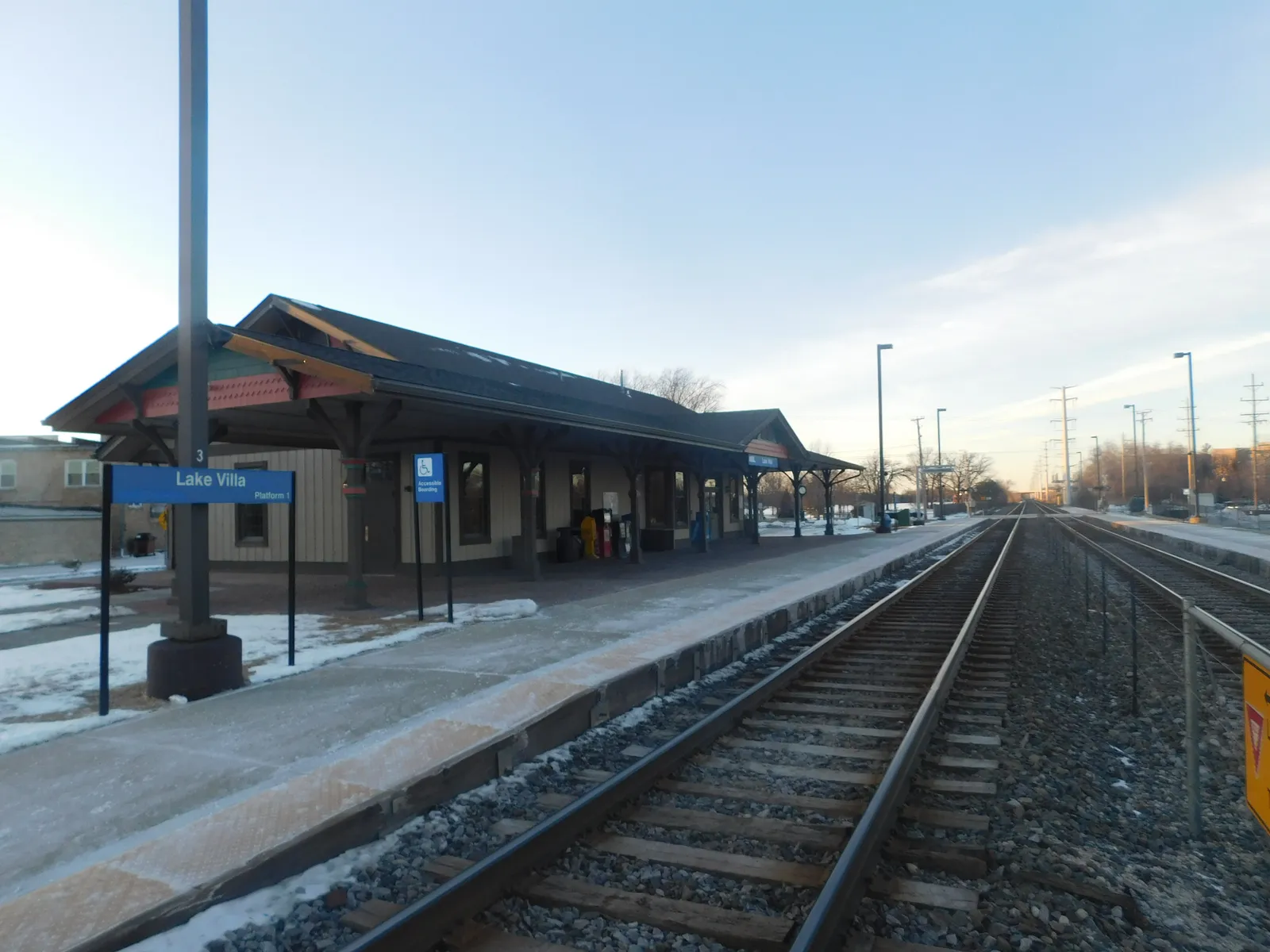 Lake Villa station building, blue station sign, and railway platforms in winter