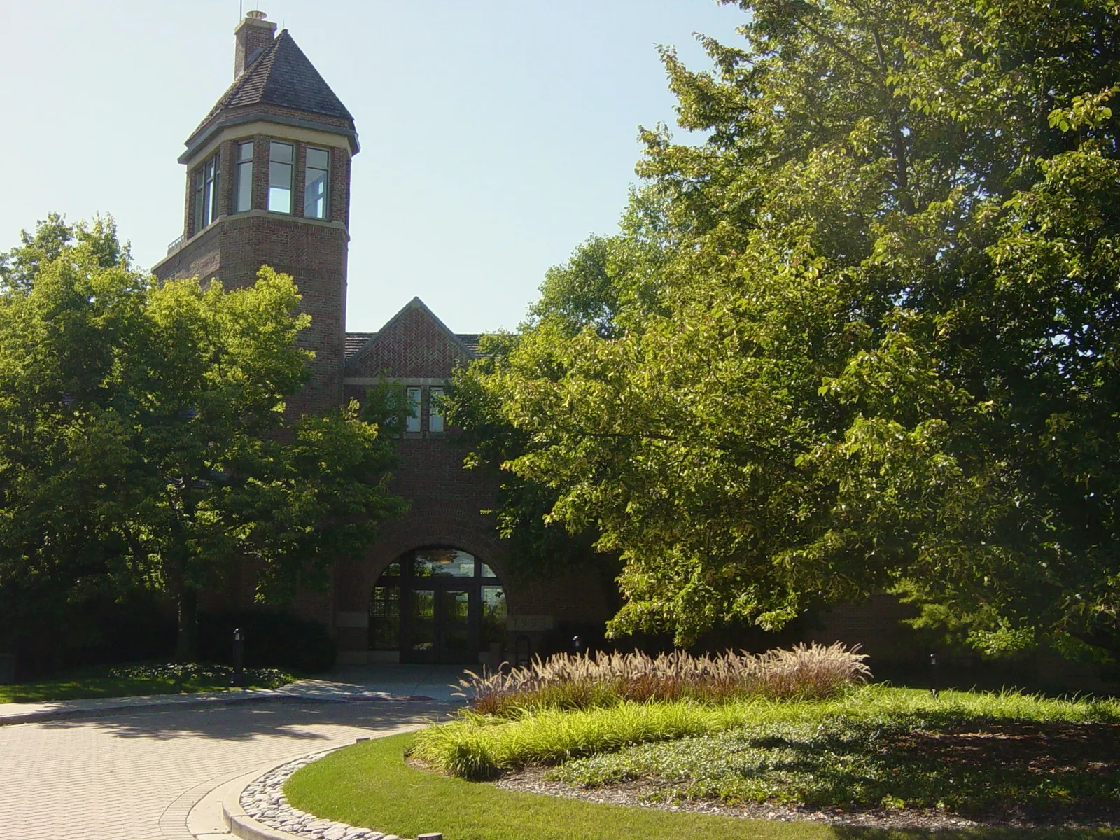 Brick tower and arched entrance of Lincolnshire Village Hall behind leafy trees in August 2008